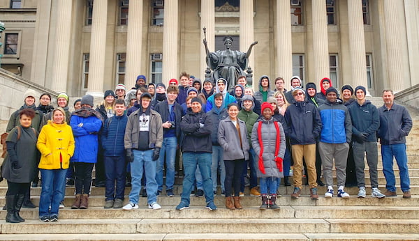 A group of people posing for a photo in front of a statueDescription automatically generated